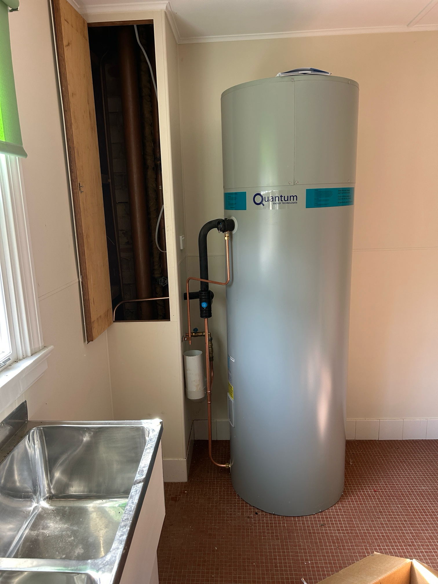 Tall, Gray Water Heater Next to a Dark Wall Opening — Croker Plumbing and Gas in Goulburn, NSW