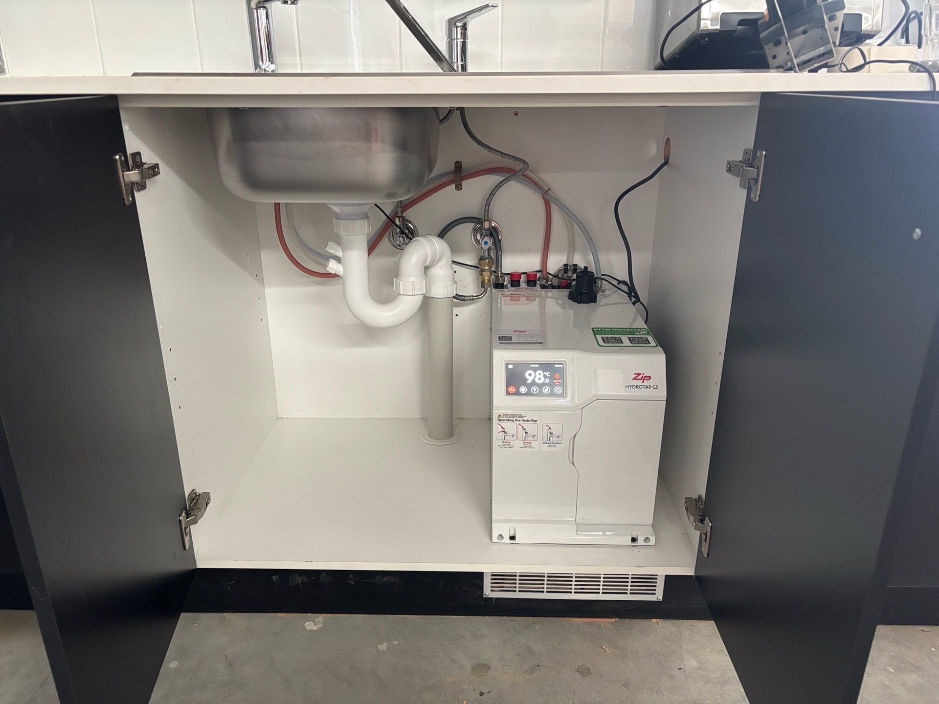 Cabinet With a Sink, Plumbing, and a White Water Heater Unit — Croker Plumbing and Gas in Goulburn, NSW