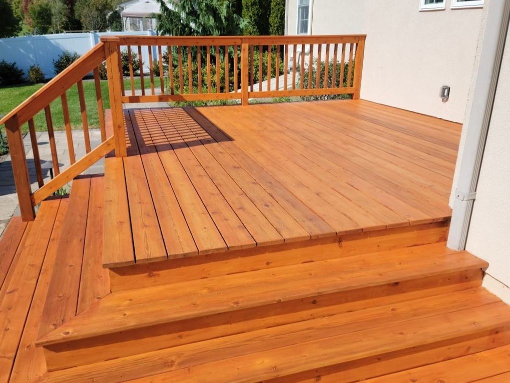 A wooden deck with stairs leading up to it and a railing work done by EK Painting in central PA