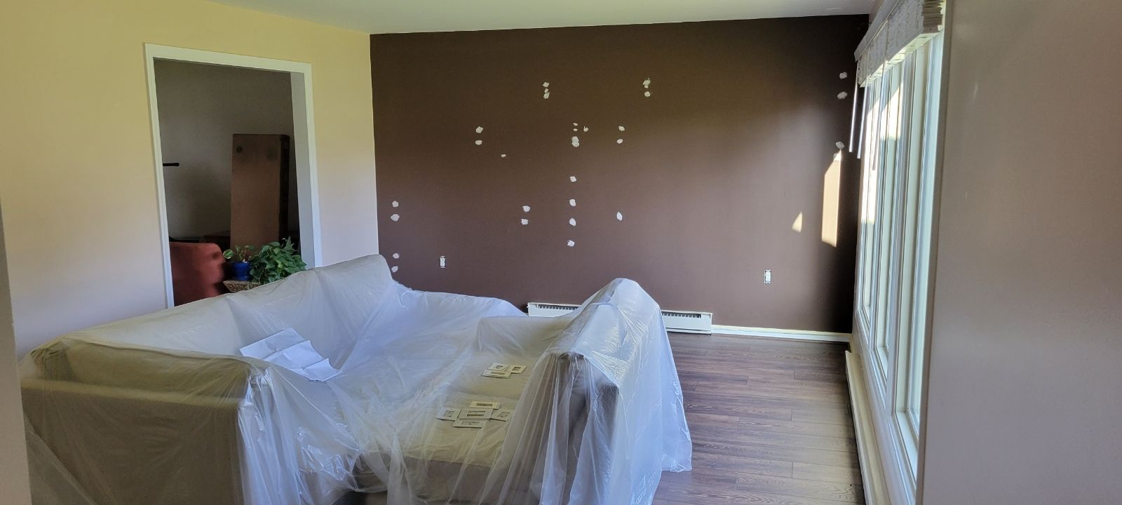 A living room with a couch covered in plastic and a brown wall work done by EK Painting in central PA