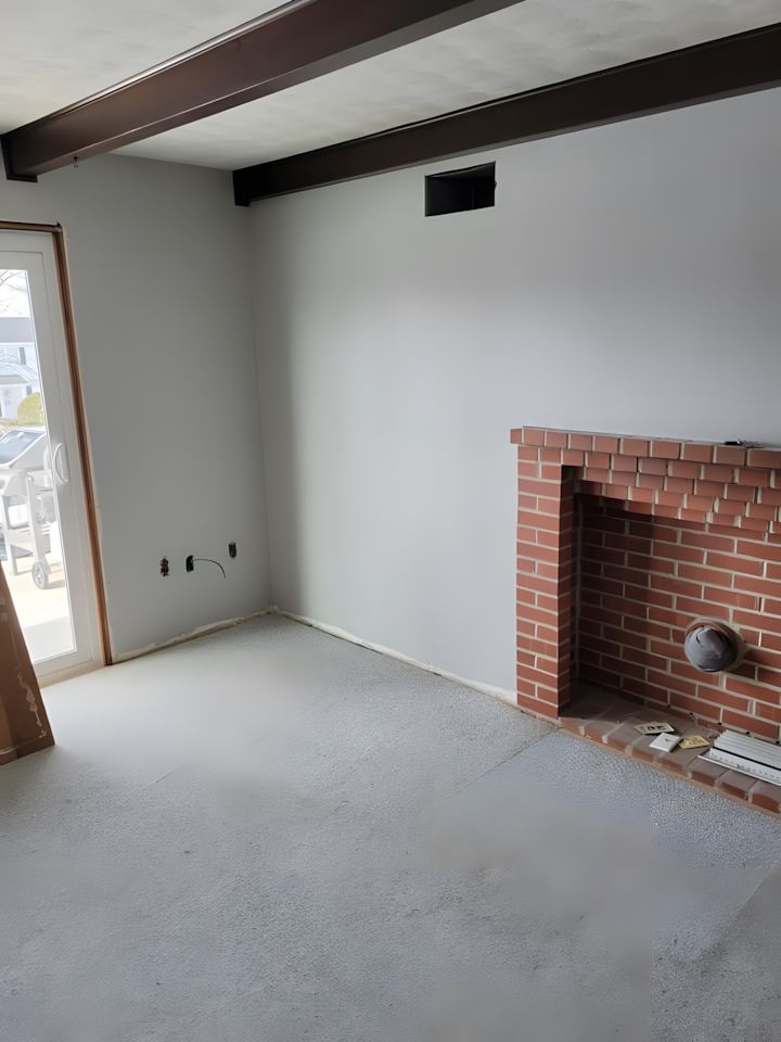 An empty living room with a brick fireplace and a sliding glass door in interior painting Morgantown, PA