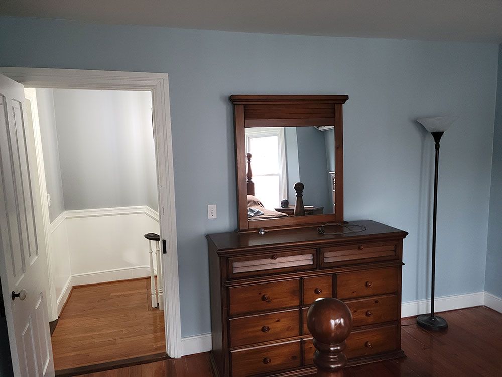 A bedroom with a dresser , mirror and lamp.