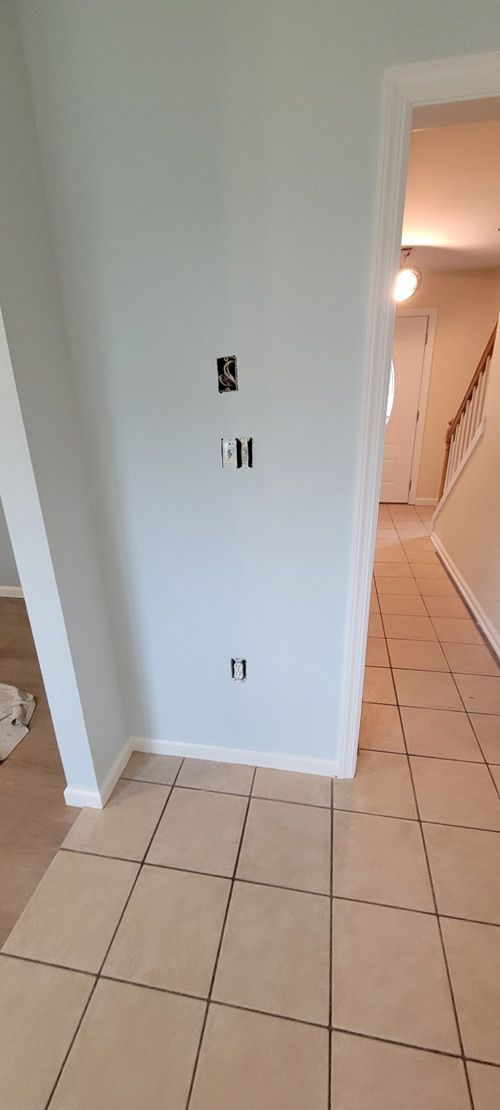 A hallway with tile floors and a white wall.