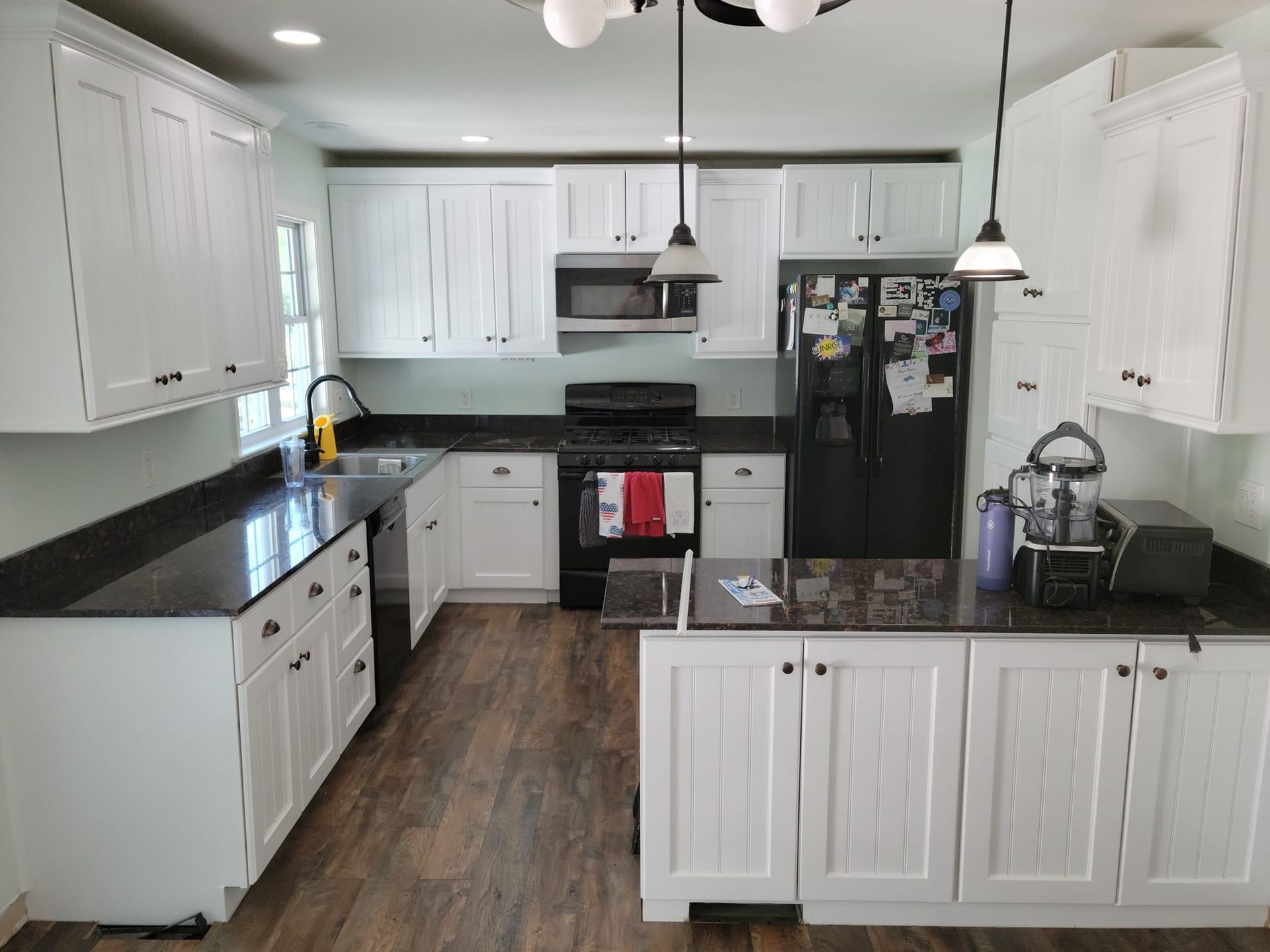 A kitchen with white cabinets and black countertops after Interior Painting in Lancaster PA.