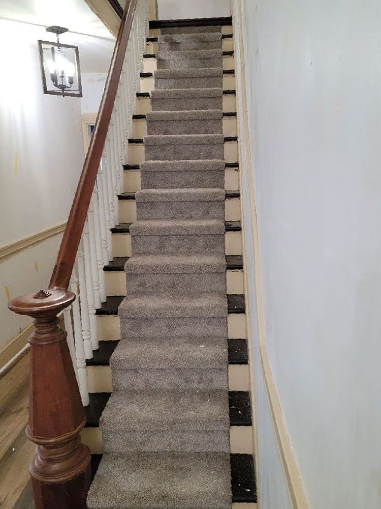 a staircase with a checkered carpet and a wooden railing .
