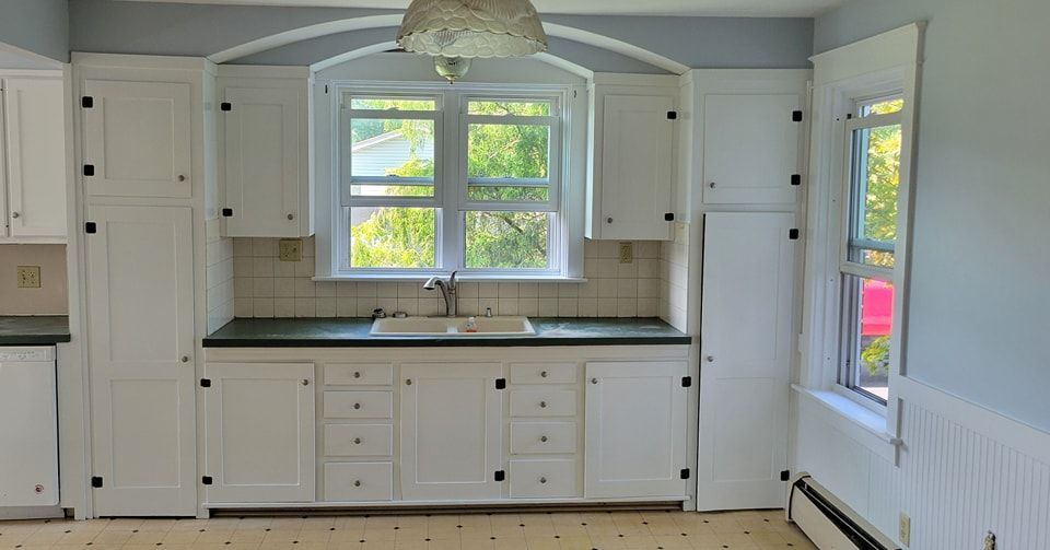 An empty kitchen with white cabinets , a sink , and a window in Bowmansville, PA