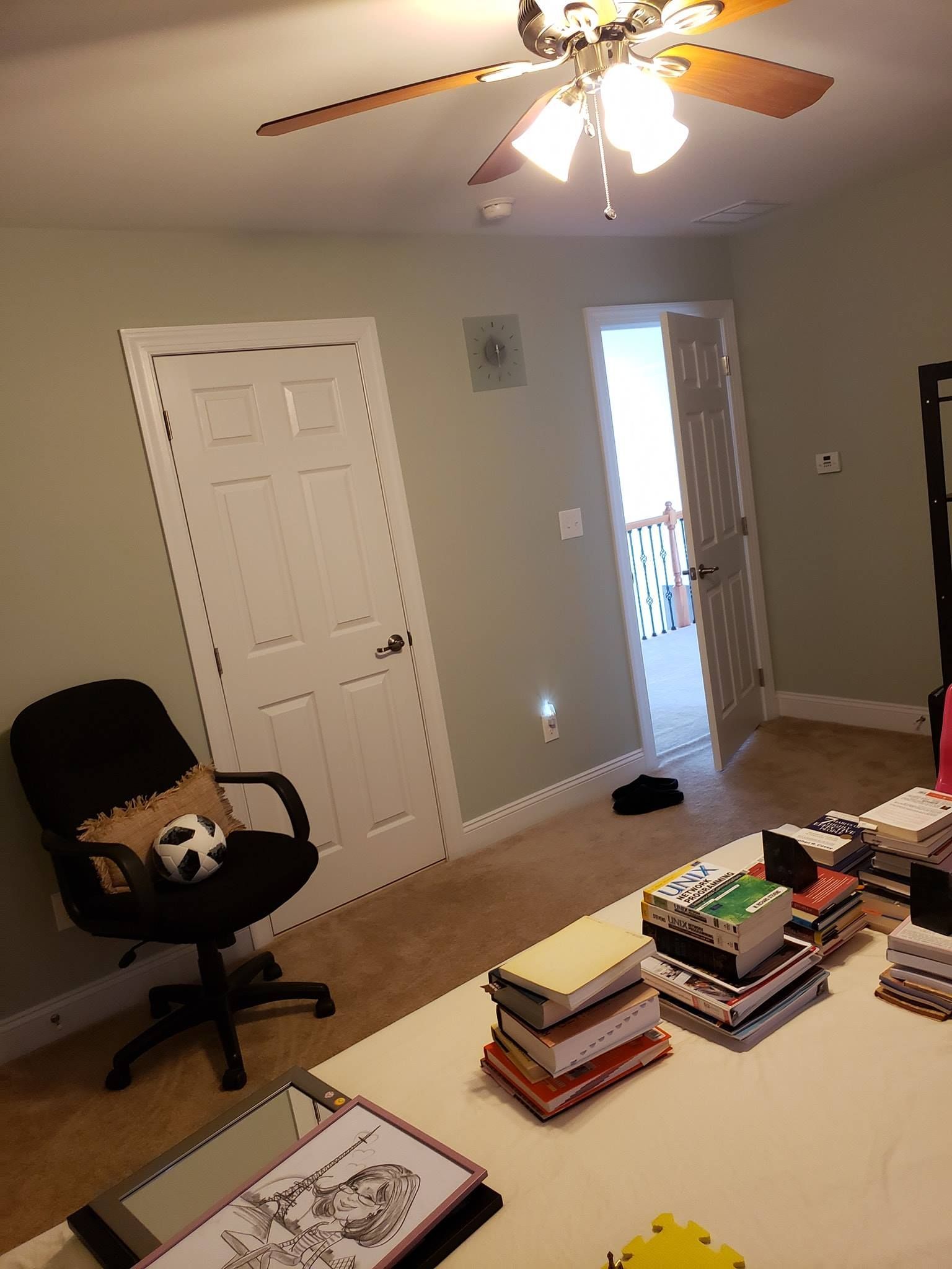 A living room with a ceiling fan and a stack of books on the table in interior painting Morgantown, PA