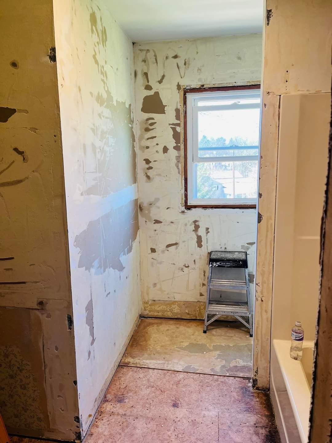 A bathroom with a window and a ladder in it