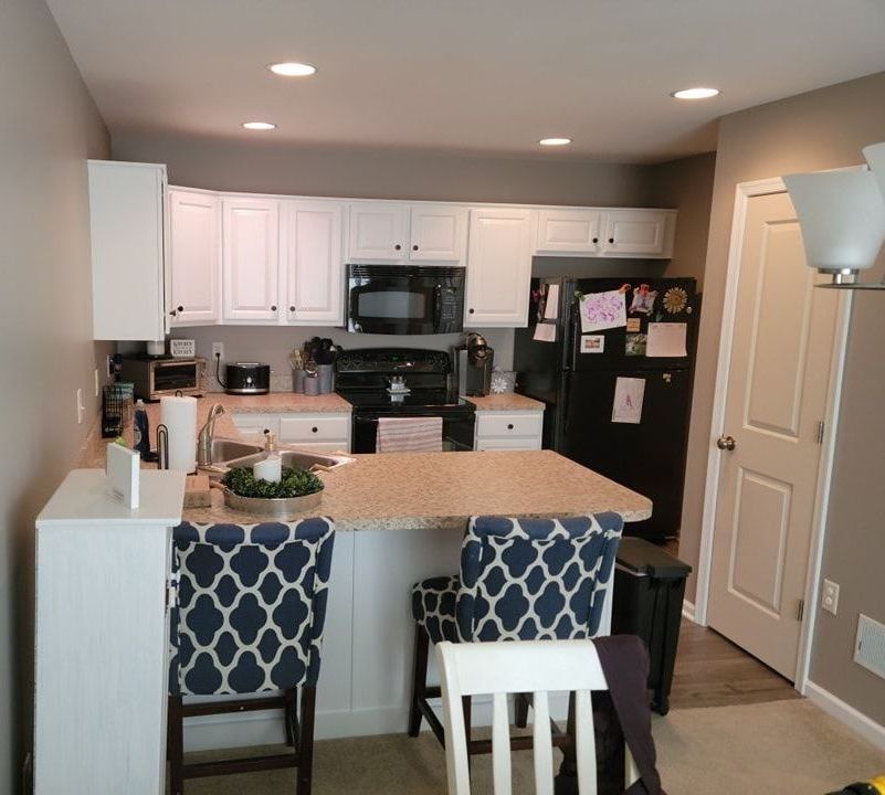 a kitchen with white cabinets and a black refrigerator painted by a local kitchen cabinet painting expert, EK Painting in Lancaster