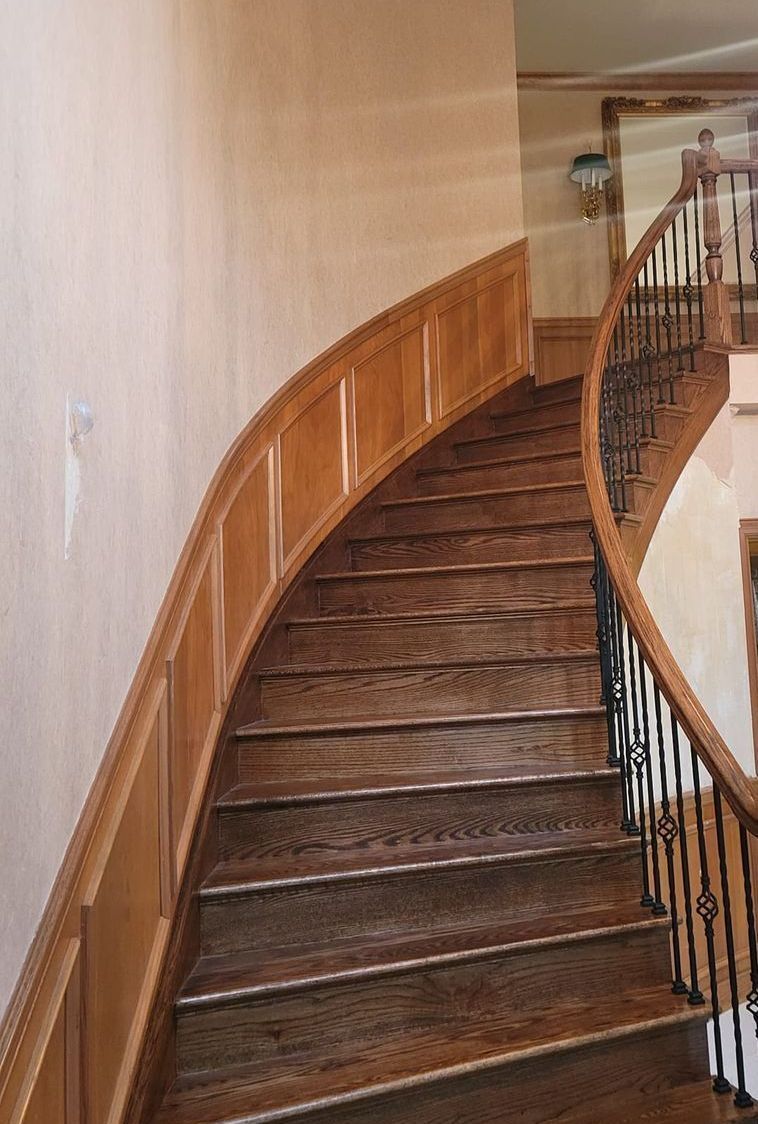 a curved wooden staircase with a wrought iron railing