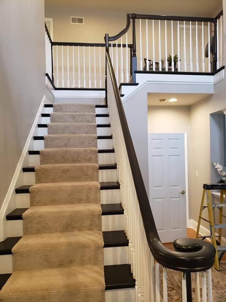 A staircase with a carpeted staircase and a black railing by EK Painting local painter for central PA