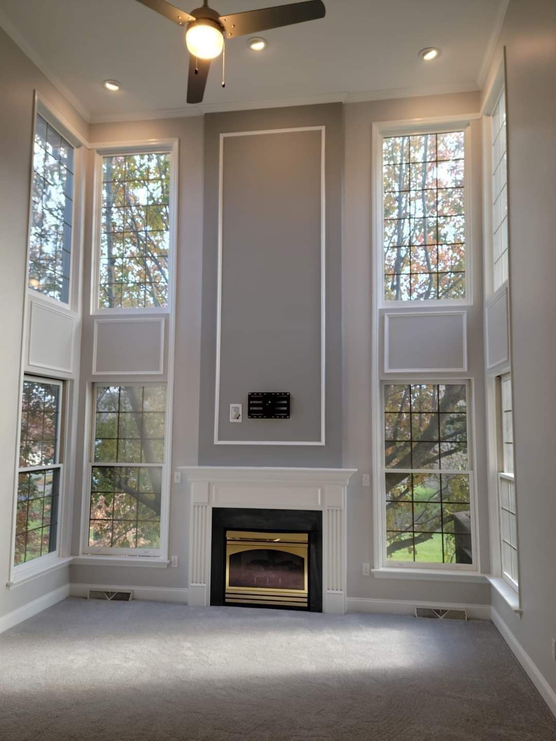 A living room with a fireplace and a ceiling fan by EK Painting local painter for central PA