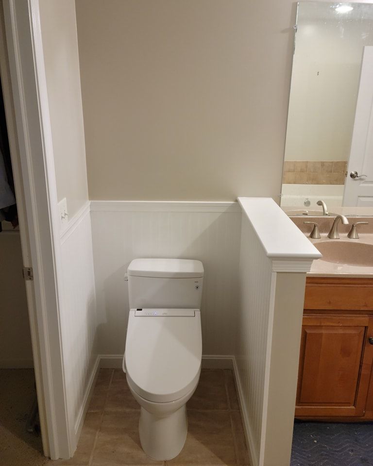 A bathroom with a toilet , sink and mirror.