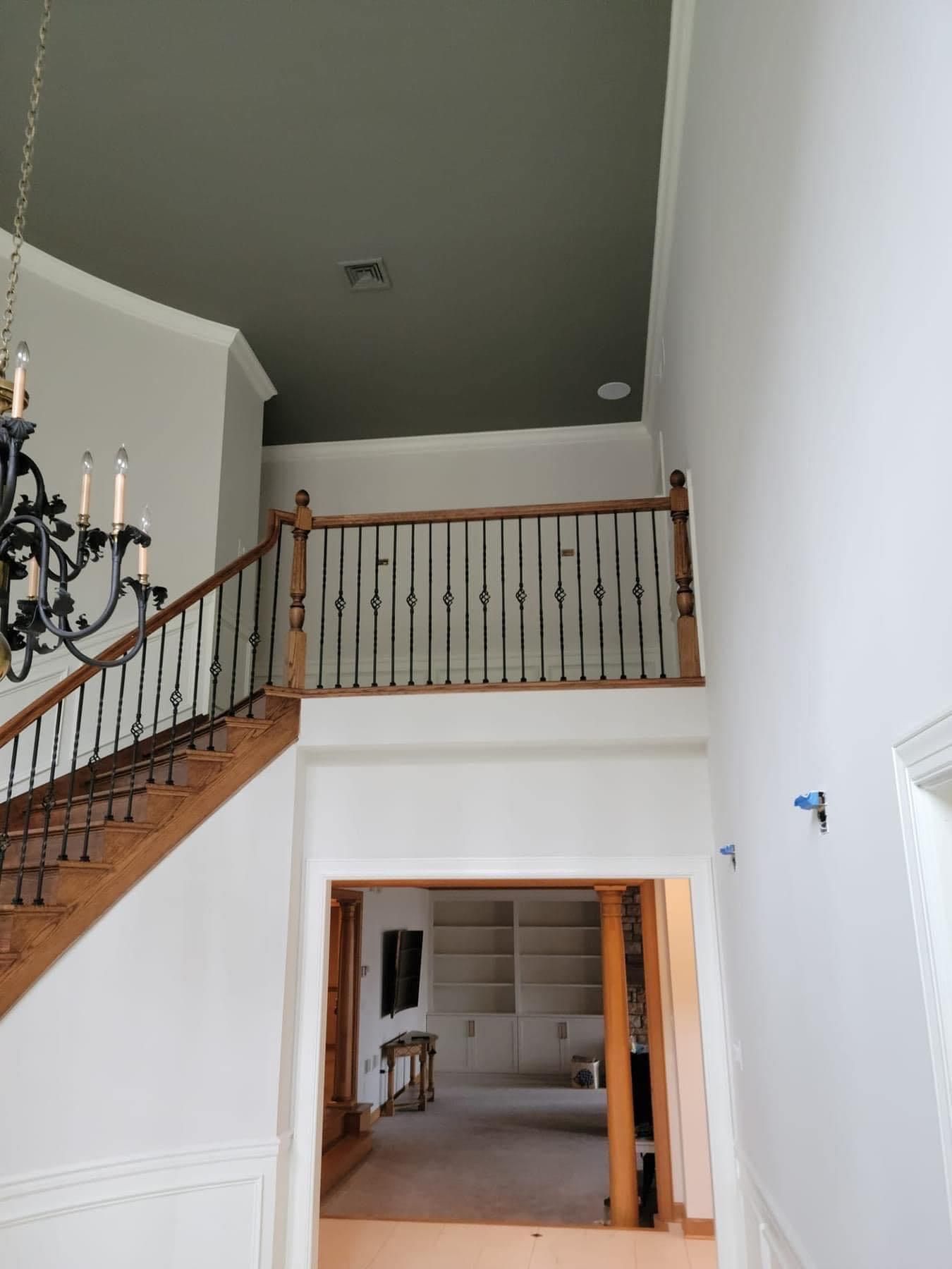 a staircase with a wooden railing and a chandelier hanging from the ceiling painted in Lancaster county by EK Painting