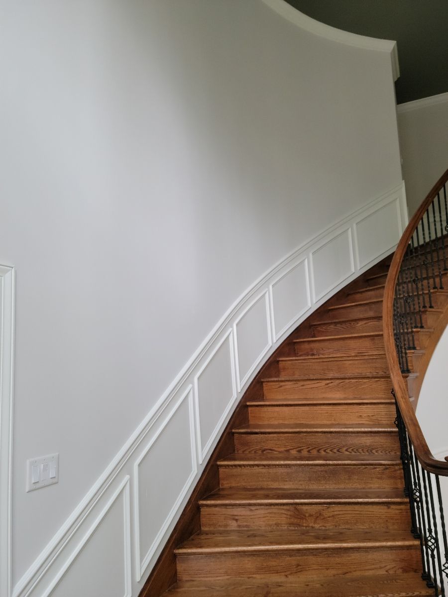 A curved staircase with a white wall and wooden steps by EK Painting local painter for central PA.