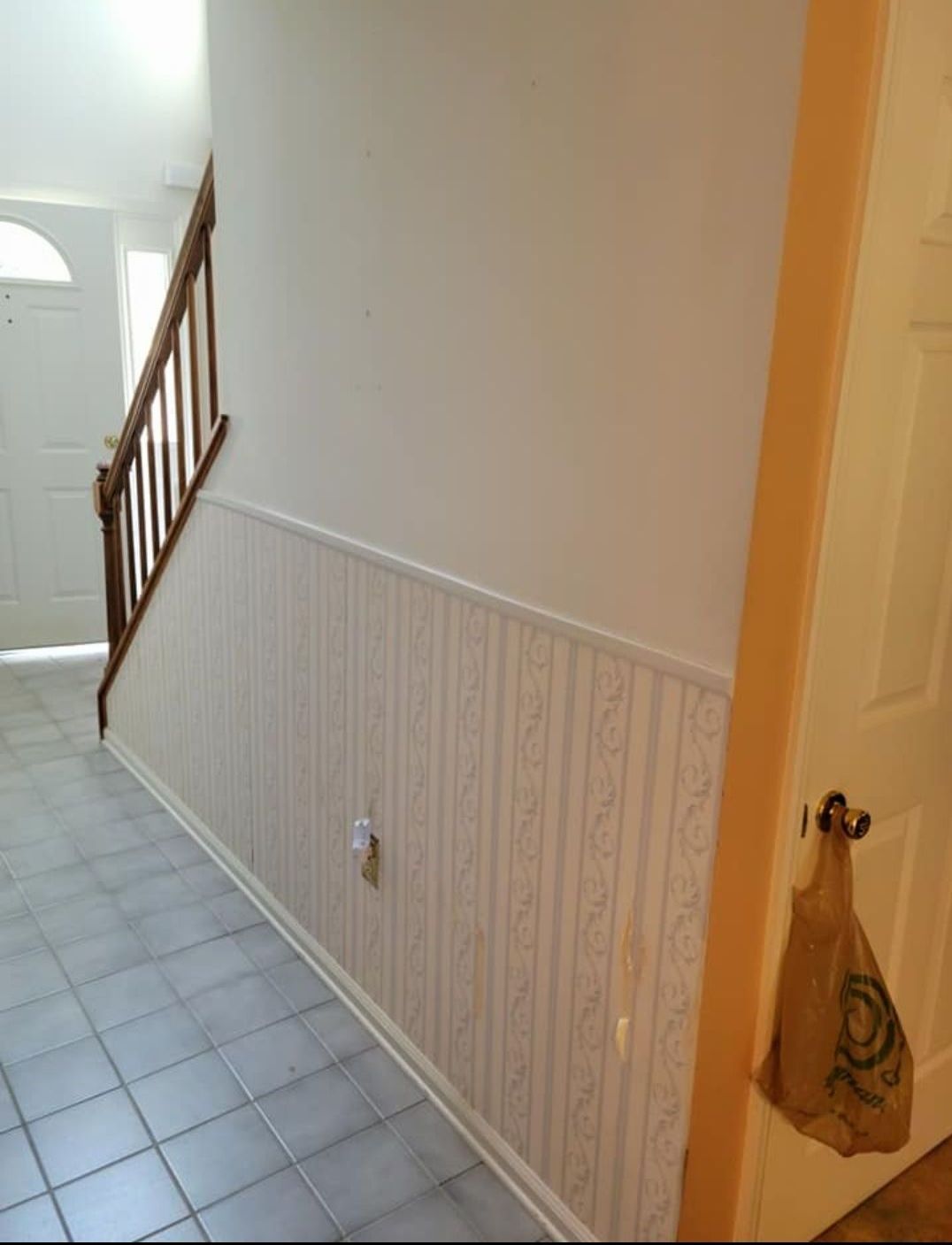 a hallway with a staircase and a bag hanging on the door