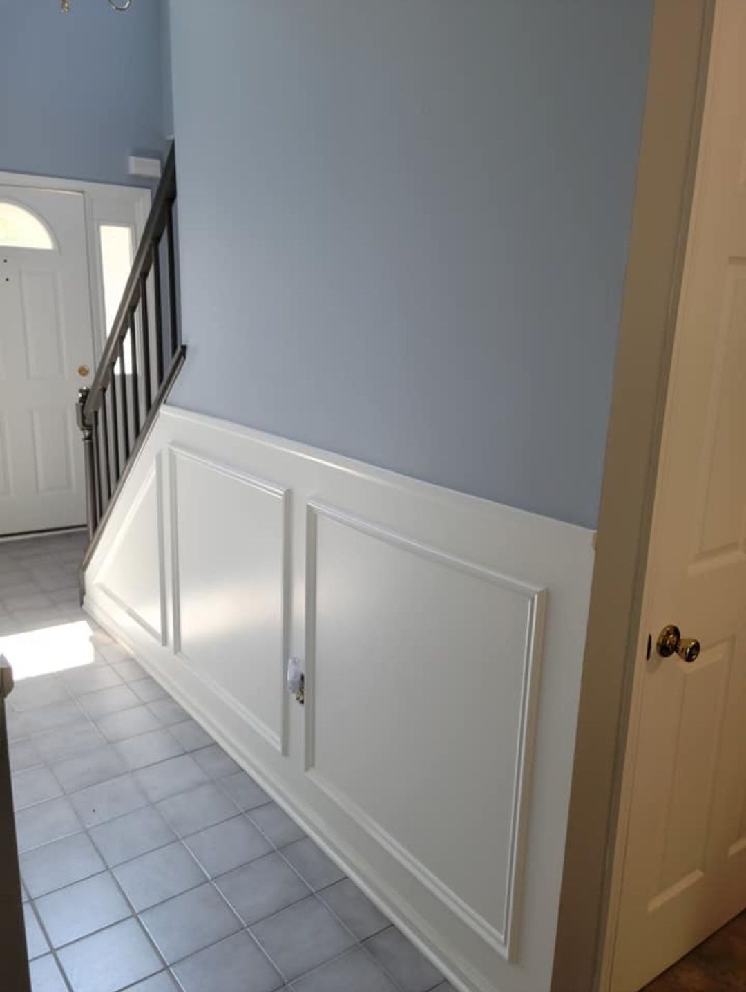 a hallway with blue walls and white trim and a staircase .