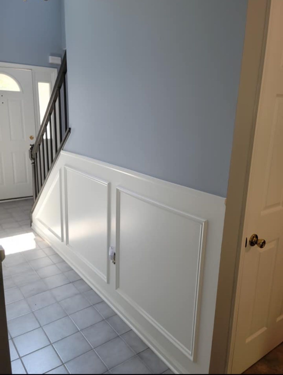 A hallway with blue walls and white trim and a staircase by EK Painting local painter for central PA