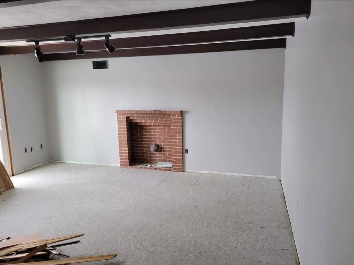 An empty living room with a brick fireplace and white walls