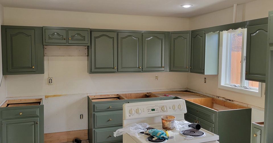 An updated kitchen with painted green cabinets and a white stove.