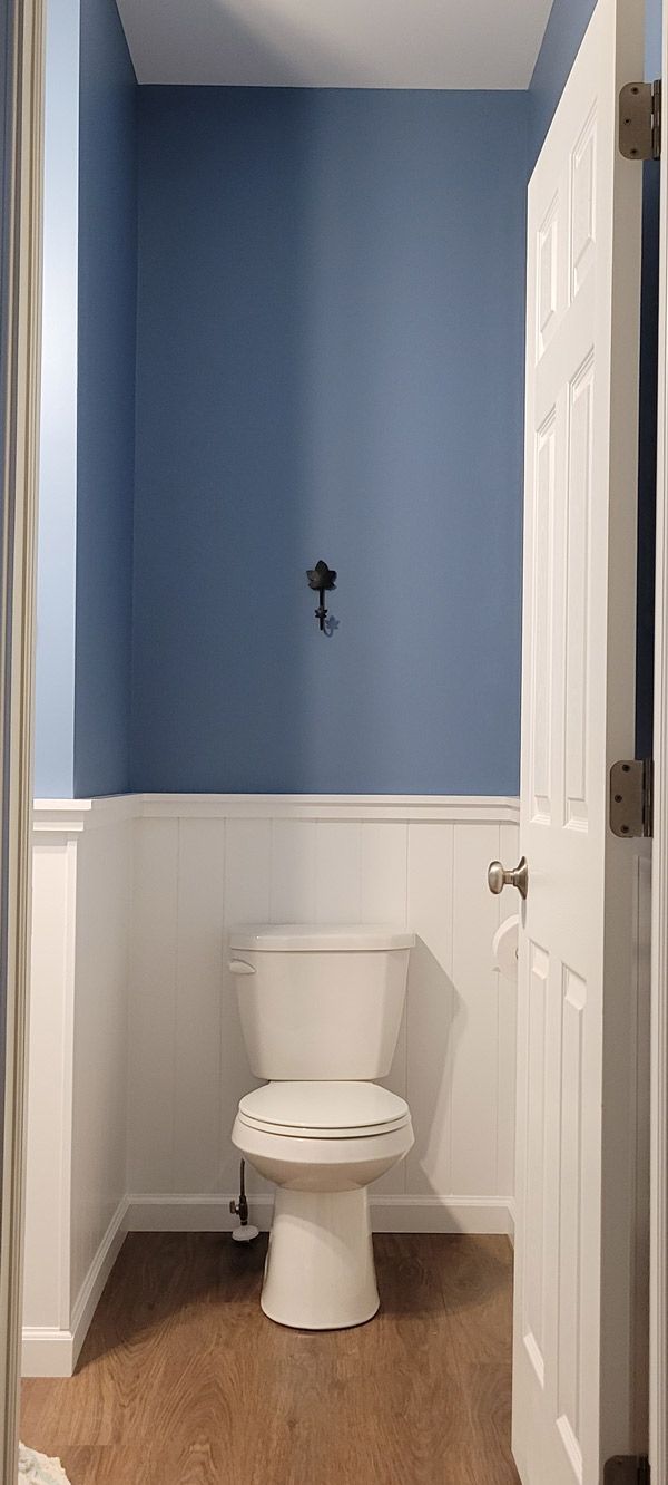 A bathroom with blue walls and a white toilet.