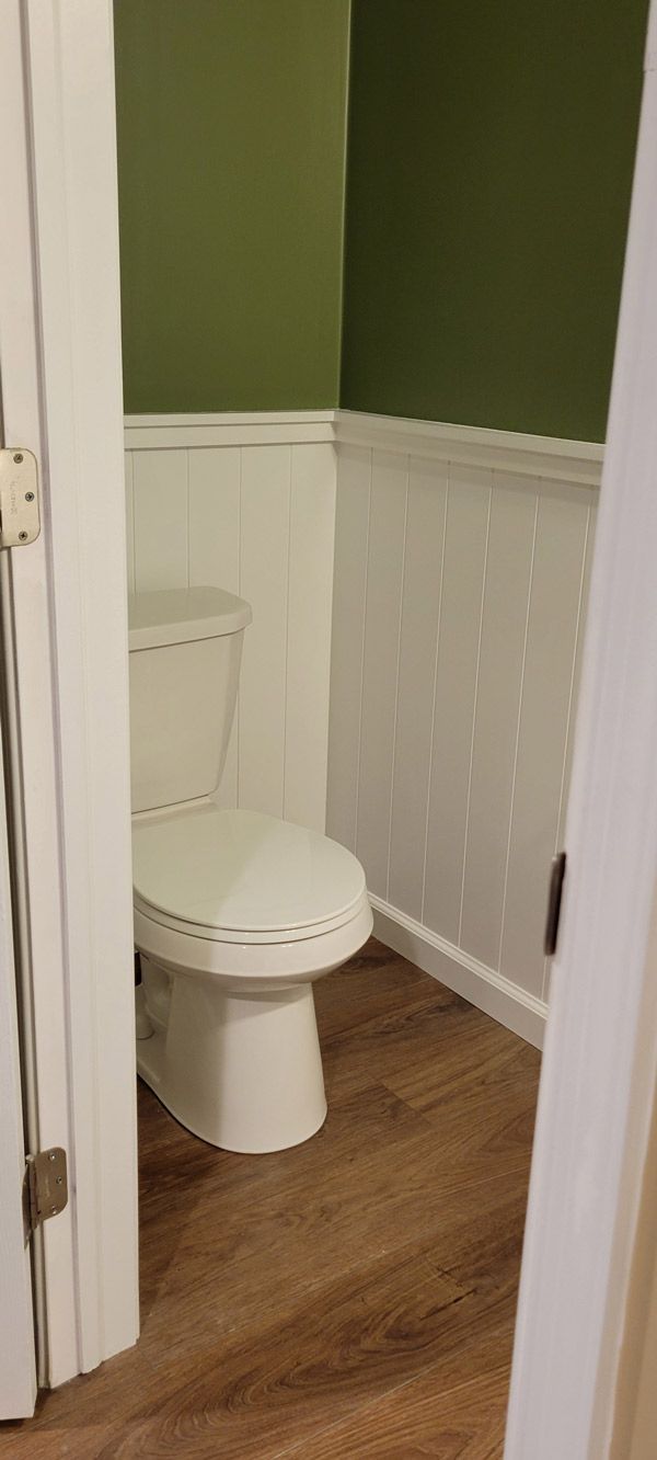 A toilet is sitting in a bathroom next to a door with new trim and paint.