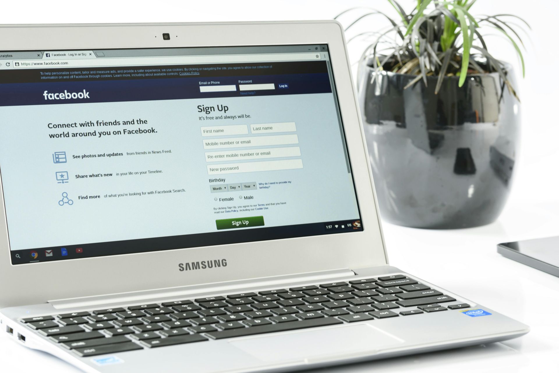 Un ordinateur portable est ouvert sur une page Facebook à côté d'une plante en pot.