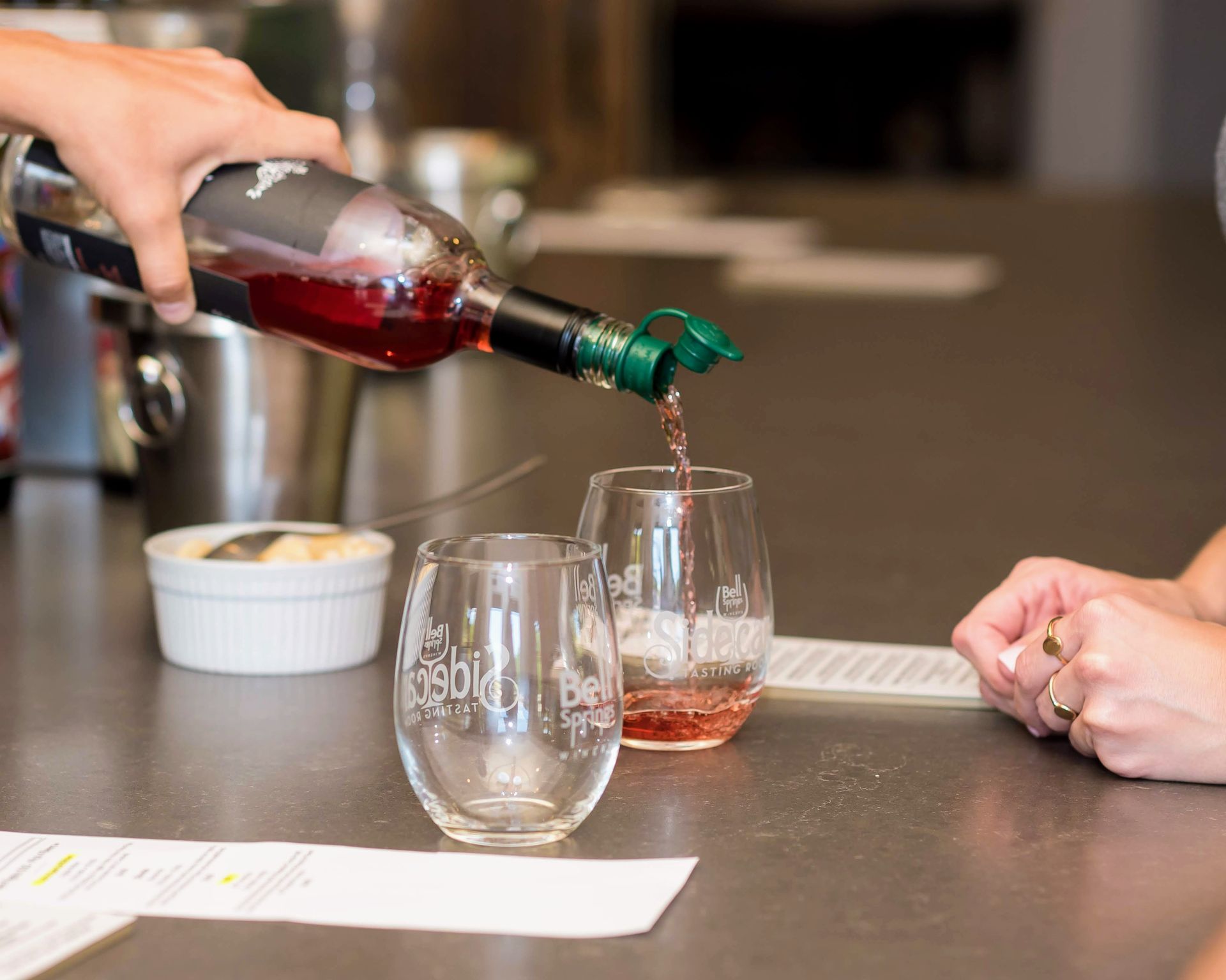 A person is pouring wine into a glass on a table.