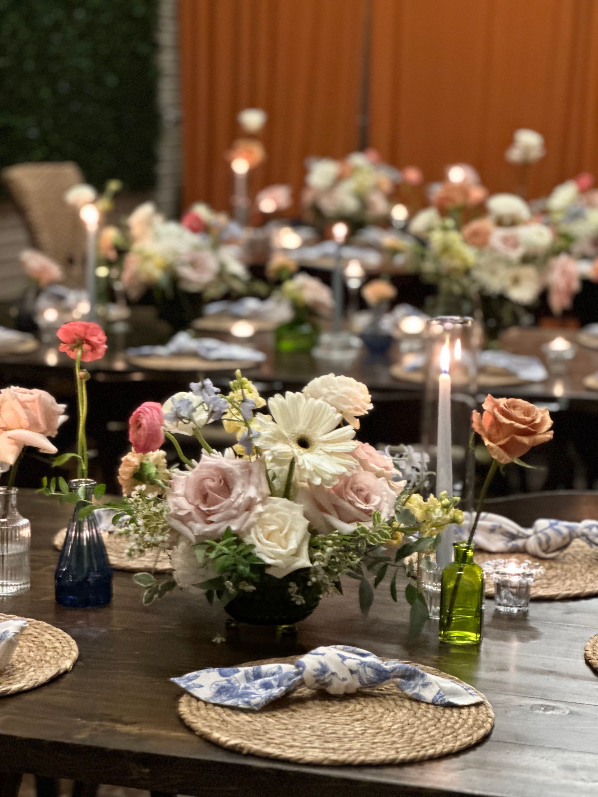 Table set for a gathering with floral centerpieces and candles.