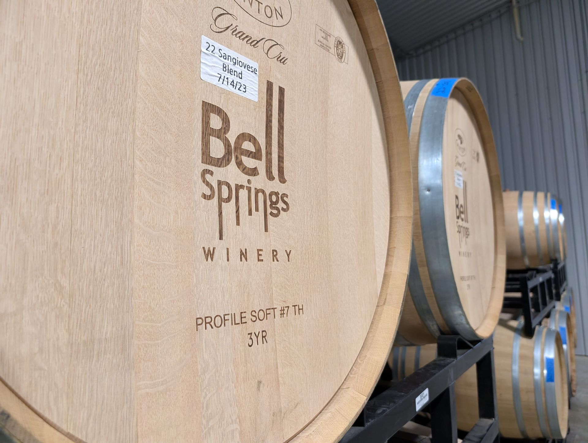 Wooden wine barrels stacked in a winery, labeled