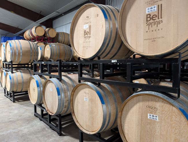 Wine barrels stacked in a winery, labeled "Bell Springs."