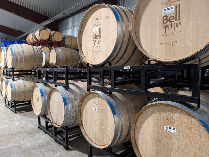 Wine barrels stacked in a winery, labeled "Bell Springs."