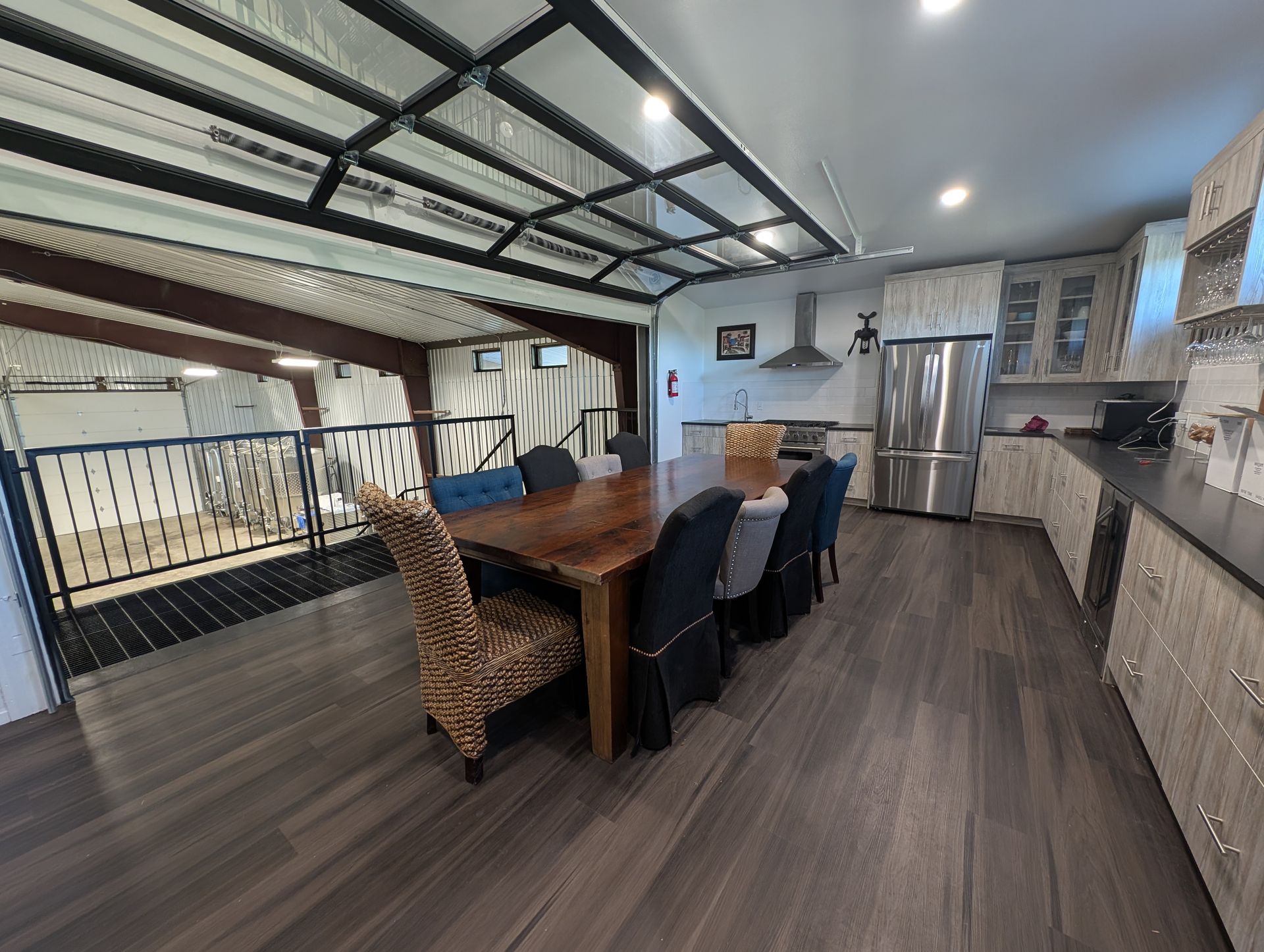 Dining area with wooden table, chairs, and kitchen; opens to a balcony overlooking a horse stable.
