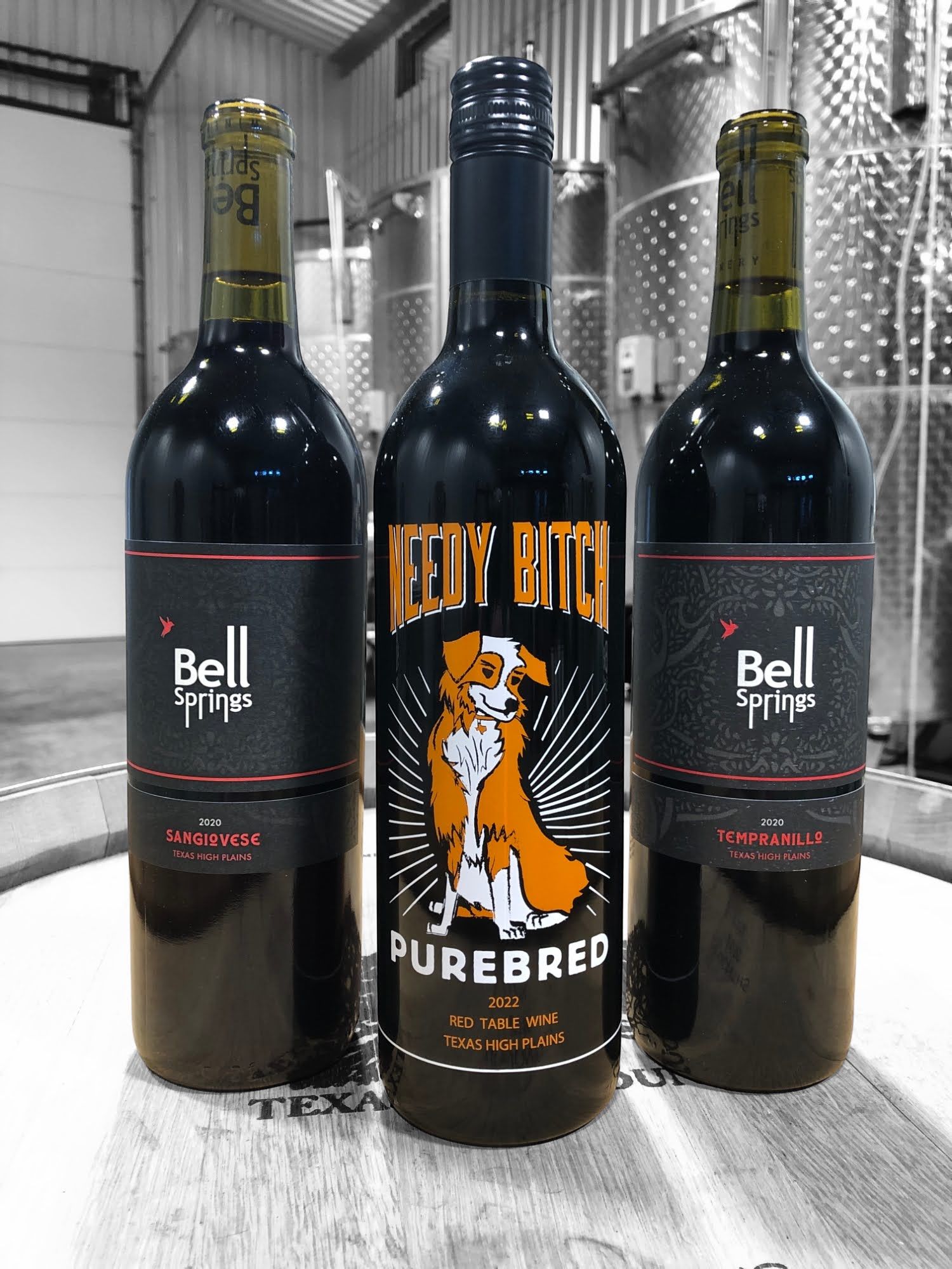Three bottles of red wine are sitting on a wooden table.