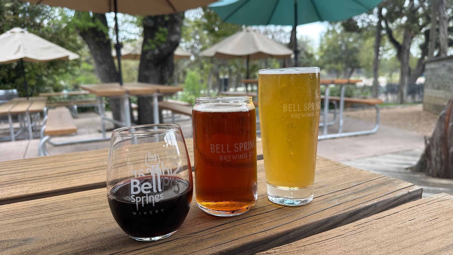 Three beer glasses on a wooden table outdoors at Bell Springs Brewing Company.