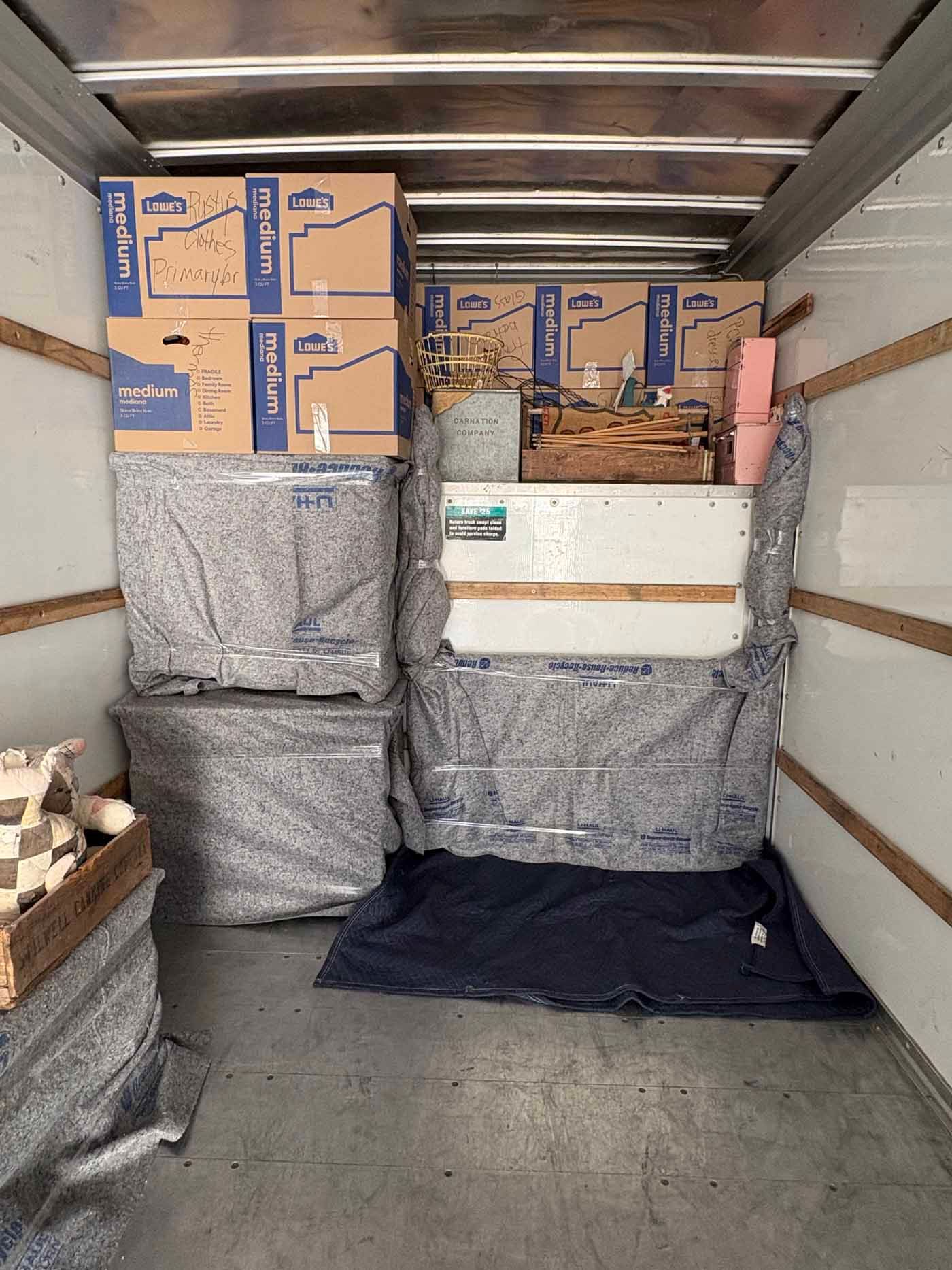 The inside of a moving truck filled with boxes and blankets.
