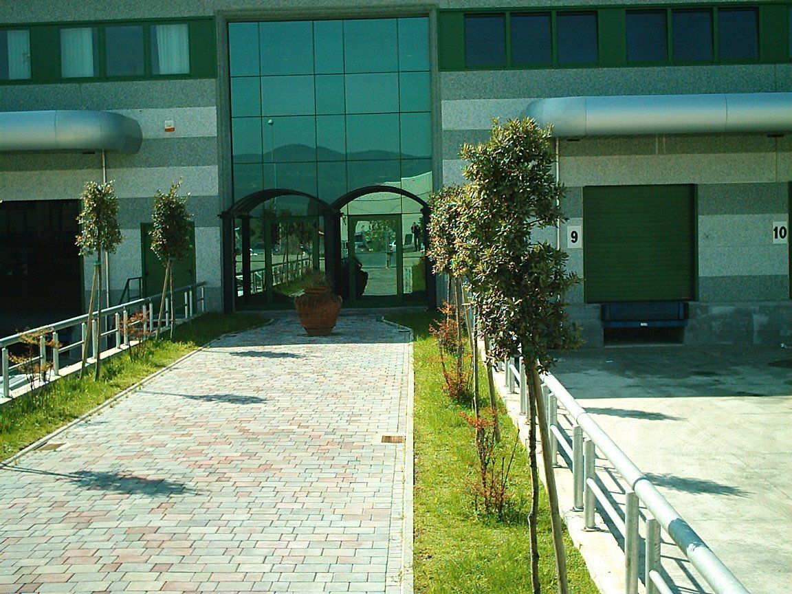 FACCIATA CONTINU STRUTTURALE CON PENSILINA D' INGRESSO IN VETRO E PENSILINE IN ALUCOBOND