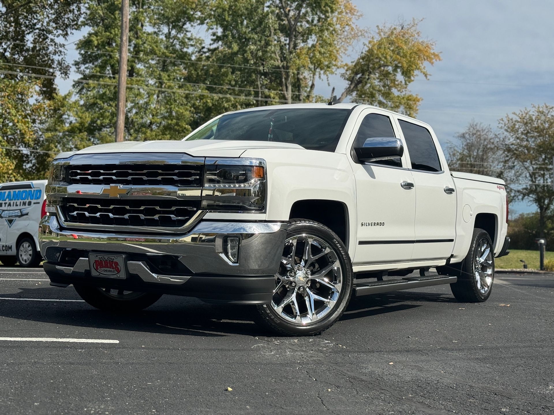 a white chevrolet silverado pickup truck is parked in a parking lot .