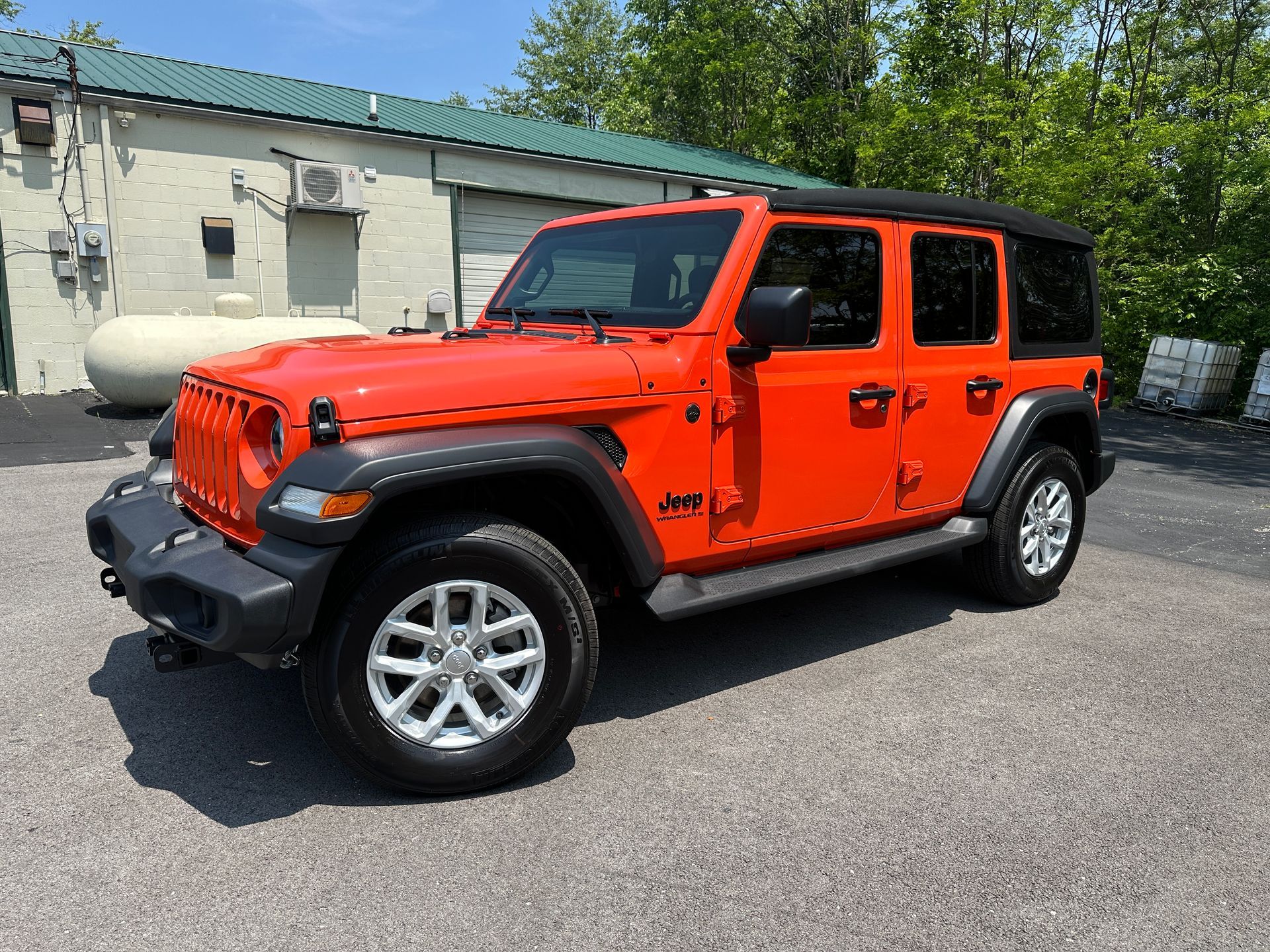 a red jeep wrangler is parked in front of a building .