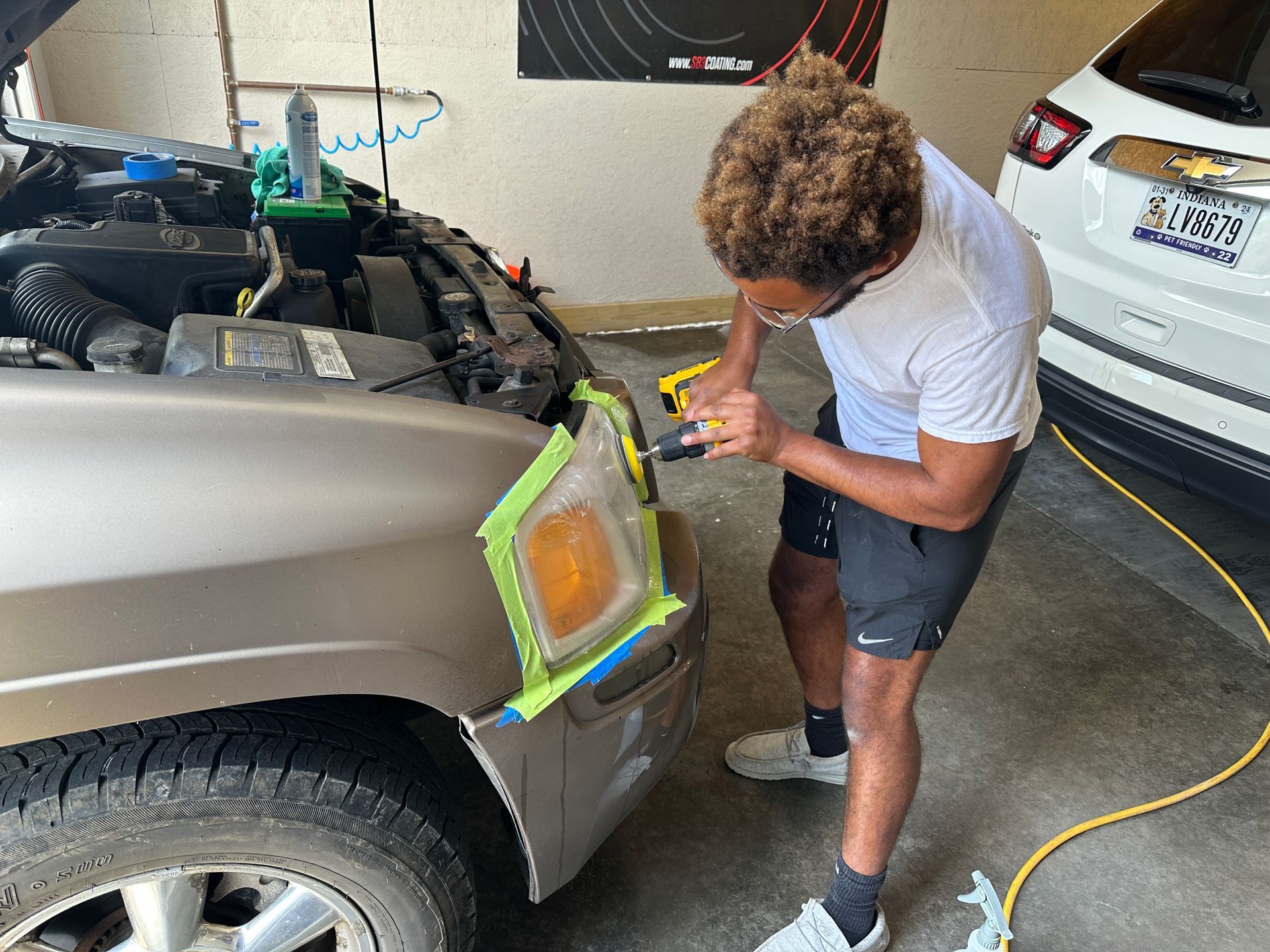 a man is polishing the headlight of a car in a garage .