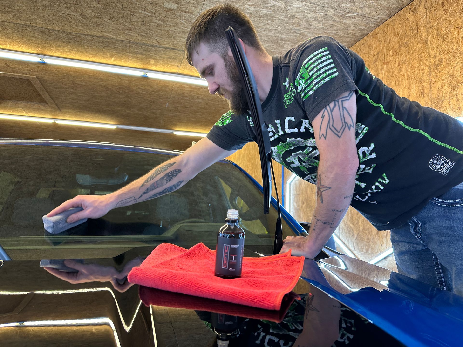a man is cleaning the windshield of a car in a garage .