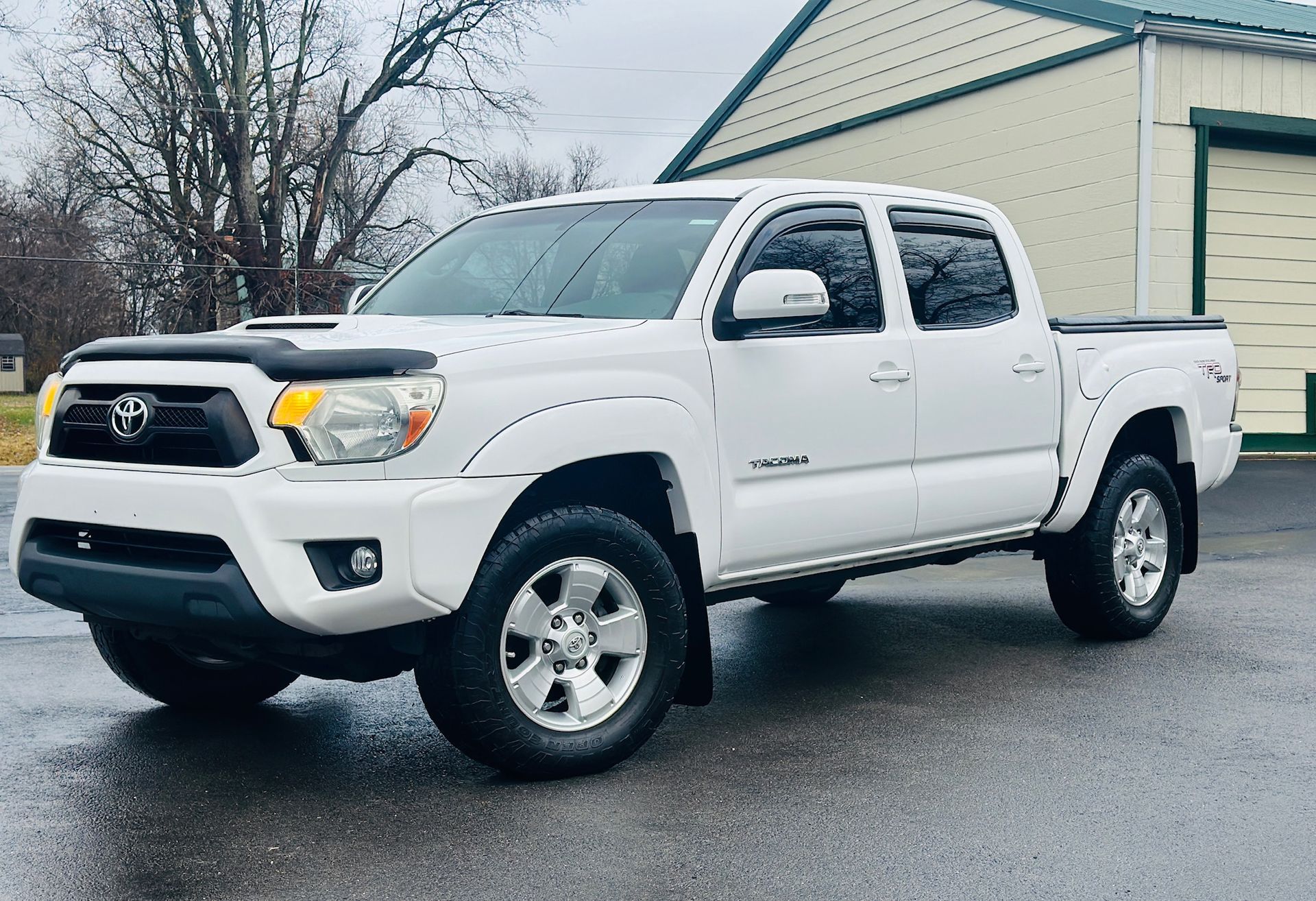 A white toyota tacoma truck is parked in front of a building.
