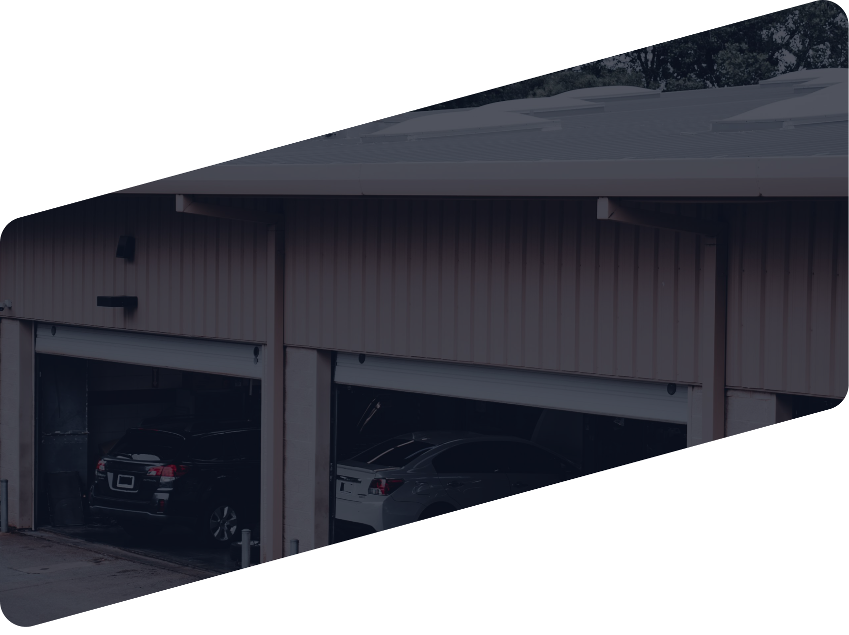 A multi-bay metal garage building with two parked cars visible inside the open bays | Ames Automotive STC
