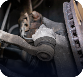 Close-up of a car's steering knuckle, showing a tie rod end attached to the wheel hub assembly near the brake rotor | Ames Automotive STC