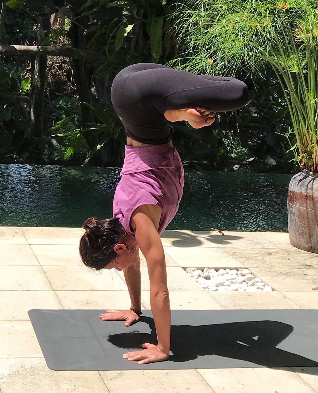 Une femme fait le poirier sur un tapis de yoga.