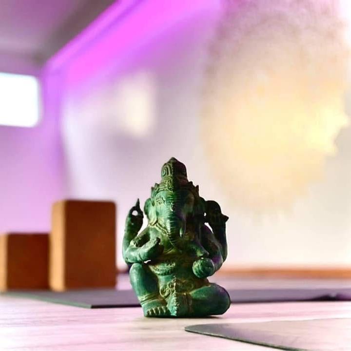 Une statue verte d'une divinité est assise sur un tapis de yoga.