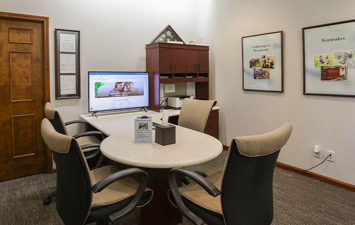 A conference room with a table and chairs and a flat screen tv