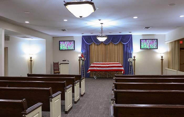 An empty church with rows of wooden benches and a podium in the middle