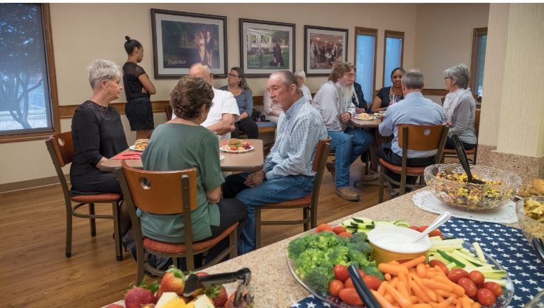 A group of people are sitting at tables in a room eating food.