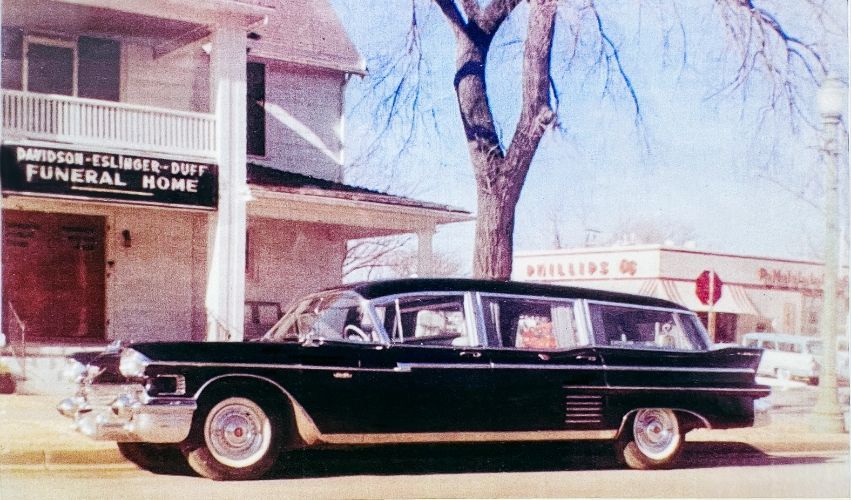 A black car is parked in front of a funeral home